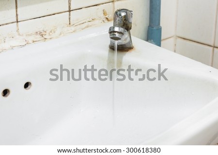 image of old sink with damaged water tap .