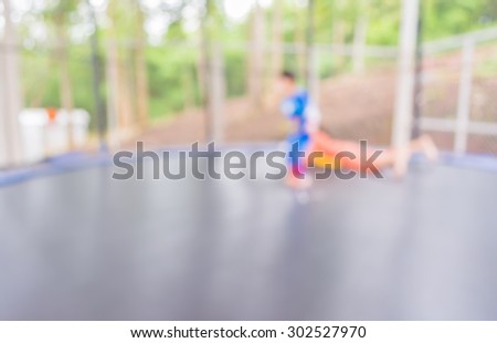 blur image of kid jumping in trampoline on day time for background usage.