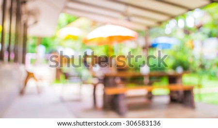 blur image of out door restaurant with green garden in background .