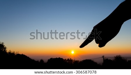 silhouette image of  hand point to the sun with sunset sky background to showing life target concept.
