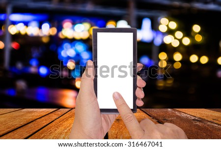 male hand is holding a modern touch screen phone and blurred bokeh background with warm orange lights (blurred).