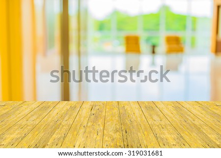 Empty top surface old yellow wooden table and blur image of hospital office room with table and chairs for background usage.
