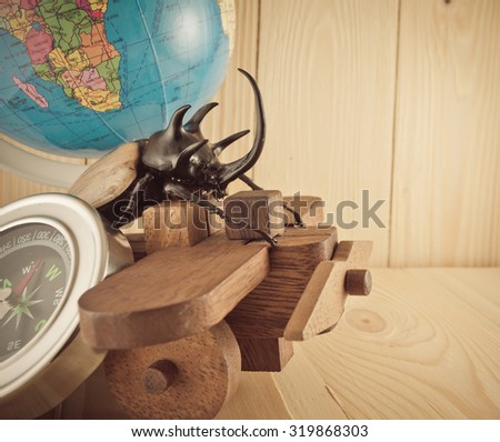 vintage tone image of five horn beetle and wooden plane on  pine wood table background.(selective focus on beetle)
