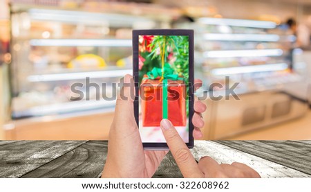 male hand is holding a modern touch screen phone and Blur image of people in bakery shop for background usage .
