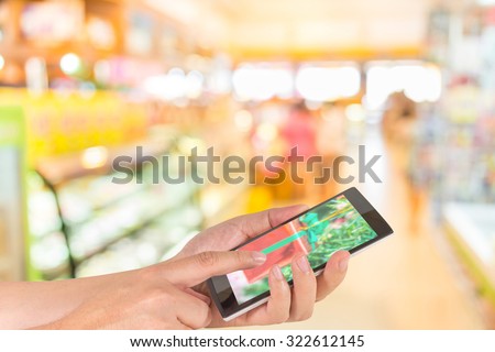 male hand is holding a modern touch screen phone and image of food store blur  with bokeh for background usage.