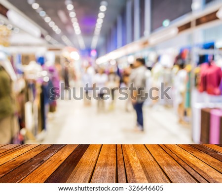 blurred image of wood table and trade show in shopping mall for background usage .
