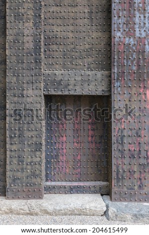 Heavy metal reinforcement on wooden door-frame in Japanese fortification, showing details of rivet and metal corrosion.