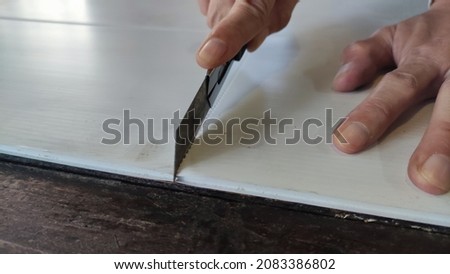 The hand is holding the cutter to cut the flute Board. Photo stock © 