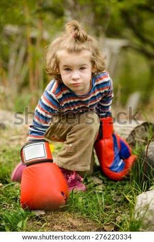 Little girl in boxing gloves playing in garden. Long Shot. LS.