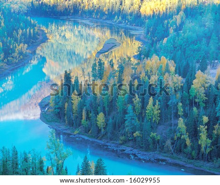 The colorful autumn mountain forest and blue curving river in Sinkiang province,China,looks like an oil painting.