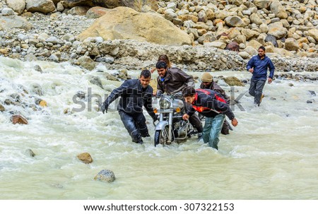 Spiti valley,India - July 16,2015 : Bikers helping each other to cross through Himalayan glacial waterfall at Himachal Pradesh, India