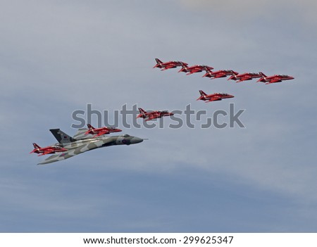 July 2015. Royal International Air Tattoo, RAF Fairford, UK, British Aerospace Hawk jet trainers of the Red Arrows are seen in delta formation with the last flying Avro Vulcan jet bomber.