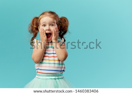Portrait of surprised cute little toddler girl child standing isolated over blue background. Looking at camera. hands near open mouth Stockfoto © 