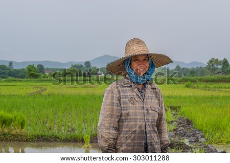 LOEI,THAILAND-AUGUST 2,2015: Happy agriculture woman with green field in raining day