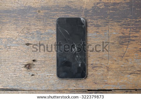 Top view of Broken glass of smart phone on the grunge wood.