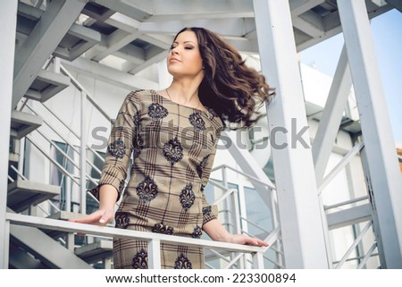 Fashion lady, sensual brunette woman with shiny curly silky hair in elegant dress. Outdoor shot