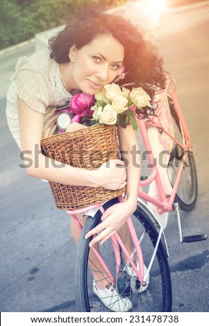 Beautiful Girl on a pink vintage Bike with basket full of flowers