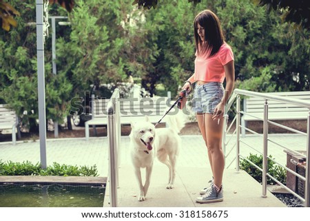 Young girl and her husky dog walking in autumn in a city park. Training the dog.