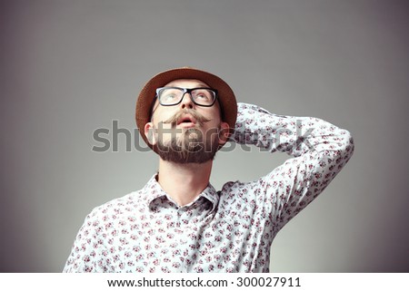 Portrait of young hipster looking upwards and thinking
