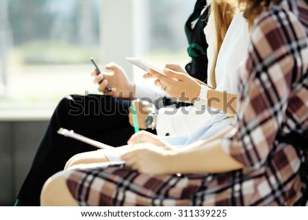 Students sitting in a row with cell phones, pens and notebooks