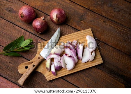Chopped onions and knife on wooden chopping board, laurel leaves , kitchen cloth on a nice rustic background