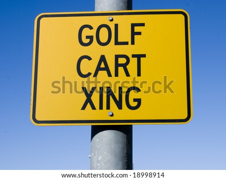 A clear sign posted on a road alongside a golf course