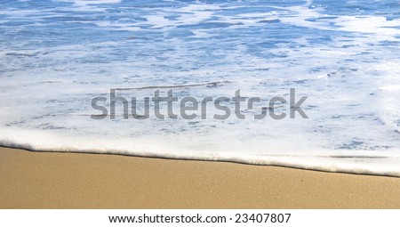 Gentle surf lapping against golden sand. Focus on water\'s edge.