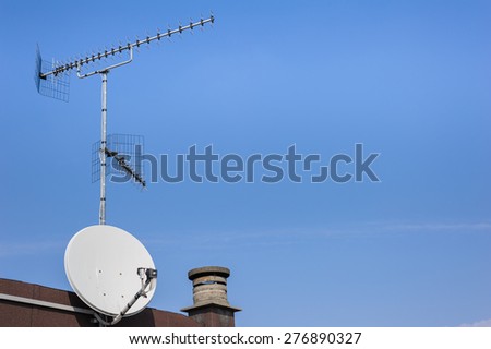 TV aerial and satellite dish against a blue sky