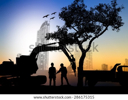 silhouette man worker with Loaders and trucks in a building site over Blurred city