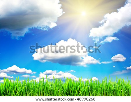 Green grass under blue sky with clouds and spring sun