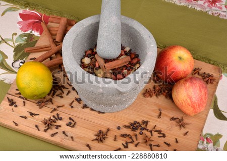 stone pestle grinding anise, nuts, pepper and cloves on wood