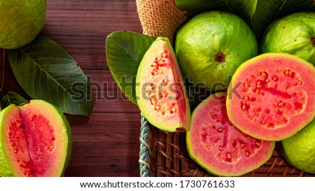 Closeup of a red guava cut in half, in the background several guavas and green leaf 商業照片 © 