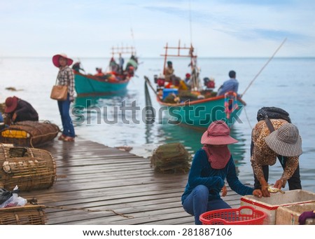 Traditional asian fishing. Cambodian men on the fishing boat pass the catch of  blue crabs to woman for sale