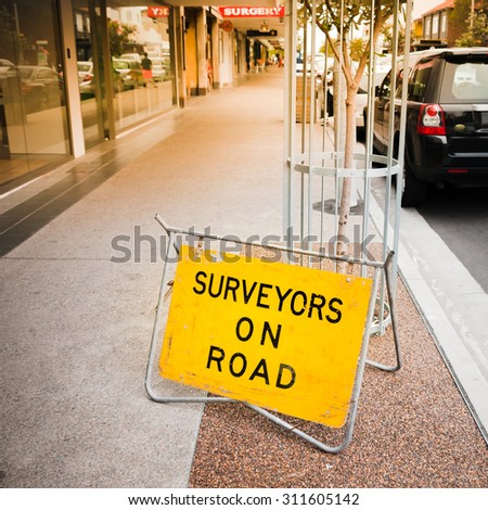 SYDNEY, AUSTRALIA - DECEMBER 10, 2014: Surveyors on road - yellow traffic sign standing on street pavement