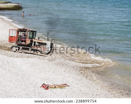 FEODOSIYA, CRIMEA, UKRAINE JUNE 3, 2011: Tractor on beach, June 3, 2011 in Feodosia, Crimea, Ukraine. The beach is one of the most popular holiday resorts in Crimea