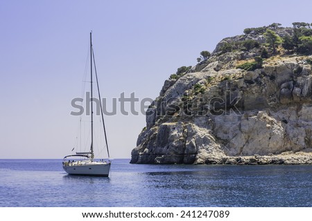 RHODES ISLAND. GREECE - JULY 27, 2014: Yacht near rocky shore of  Rhodes Island on July 27, 2014. Greek islands are popular tourist destination for many Europeans.