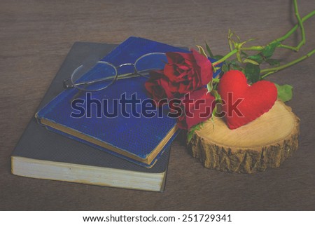 Roses on old books and glasses, small heart on timber still life, vintage style