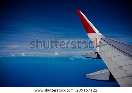 Wing of an airplane flying above the clouds. people looks at the sky from the window of the plane, using airtransport to travel