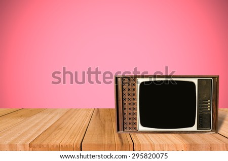 Old Style Photo. Classic vintage and retro TV on the table with pink wall background