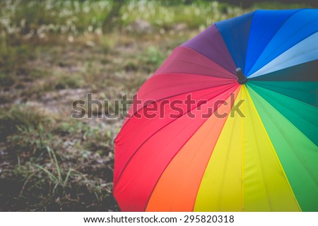 rainbow umbrella in grass field vintage and retro tone, soft focus.