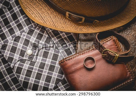 still life photography : Brown leather wallet, Leather wristbands, silver ring and adventure hat on jeans background,  men casual concept, vintage and retro style.