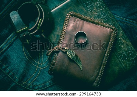 still life photography : Brown leather wallet, Leather wristbands, silver ring and adventure hat on jeans background,  men casual concept, vintage and retro style.