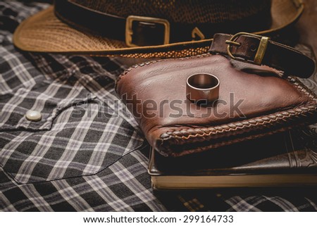 still life photography : Brown leather wallet, Leather wristbands, silver ring and adventure hat on jeans background, men casual concept, vintage and retro style