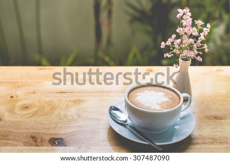latte art coffee with flowers on wooden table, vintage and retro style.