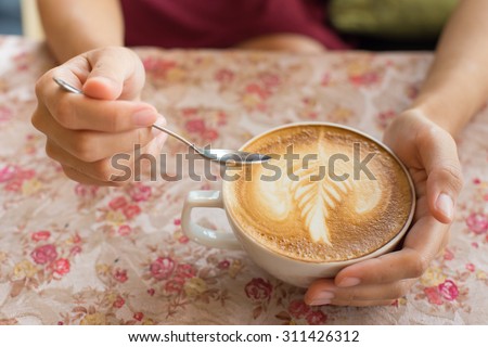 Close up image of woman shaking her favorite tasty hot art latte coffee, wearing retro white skirt and accessorizes. Shabby chic style
