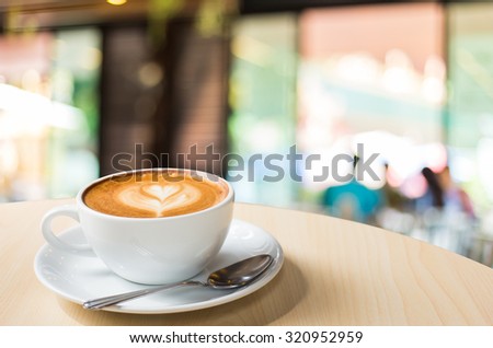 Hot art Latte Coffee in a cup on wooden table and Coffee shop blur background with bokeh image.