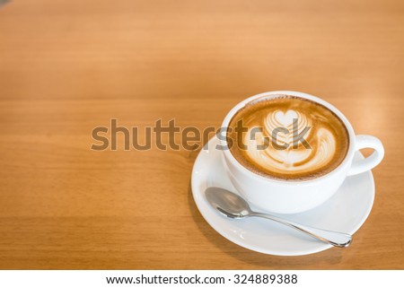 Hot art Latte Coffee in a cup on wooden table and Coffee shop blur background with bokeh image