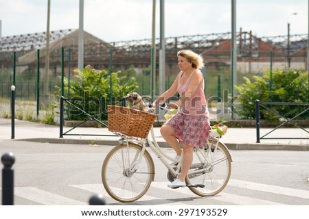 BORDEAUX, FRANCE   June 23: Woman cycling through streets of Bordeaux with Border Terrier dog in basket on front of bike, shown on 23 June 2015 in Bordeaux.