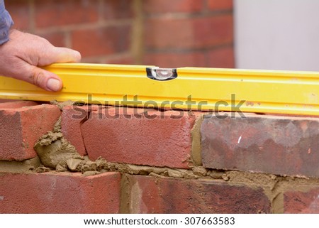 Bricklaying checking bricks are level in wall construction