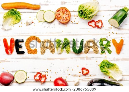 Presentation of vegan diet month in january called Veganuary. Flat lay on white rustic wooden background